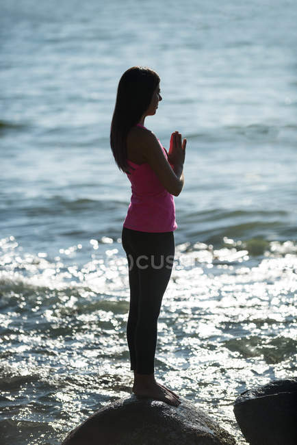 Vista lateral da mulher bonita meditando na rocha no dia ensolarado — Fotografia de Stock