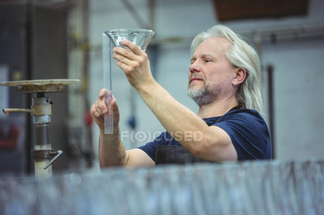 Ventilador que examina la cristalería en la fábrica de soplado de vidrio - foto de stock