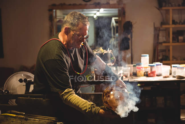 Glassblower shaping blown glass piece with wet cloth at glassblowing factory — Stock Photo