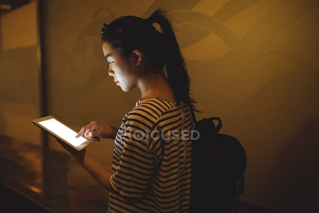 Young woman using digital tablet in passage at night — Stock Photo