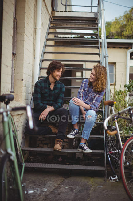 Couple assis sur les escaliers et interagissant à l'extérieur de la maison — Photo de stock
