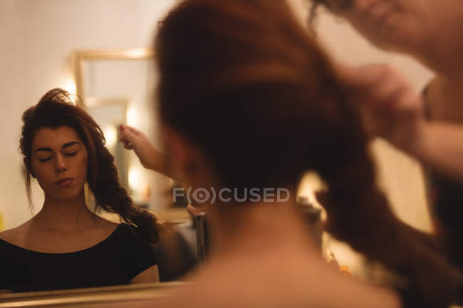 Відображення красивої жінки на дзеркалі, що укладає волосся в салоні — стокове фото