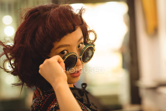 Портрет стильної жінки, що дивиться сонцезахисні окуляри — стокове фото