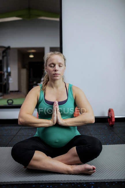 Беременная женщина, занимающаяся йогой в спортзале — стоковое фото