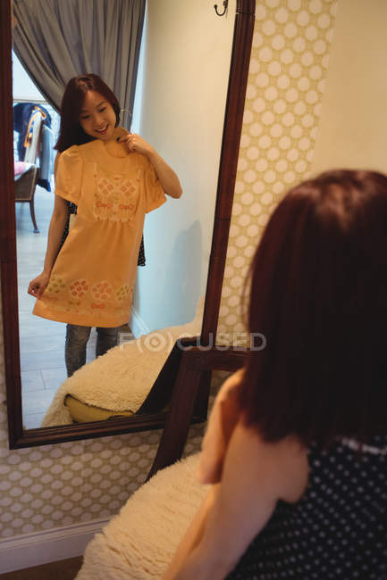 Frau schaut in Spiegel, während sie in Boutique-Geschäft ein Kleid probiert — Stockfoto
