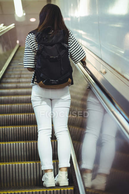 Visão traseira da mulher em pé na escada rolante — Fotografia de Stock