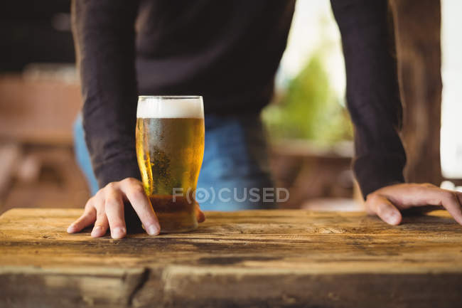 Mid section of man with glass of beer at bar — Stock Photo