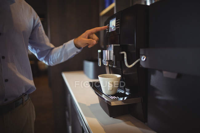 Средняя секция бизнесмена готовит кофе в кофеварке в кафетерии — стоковое фото