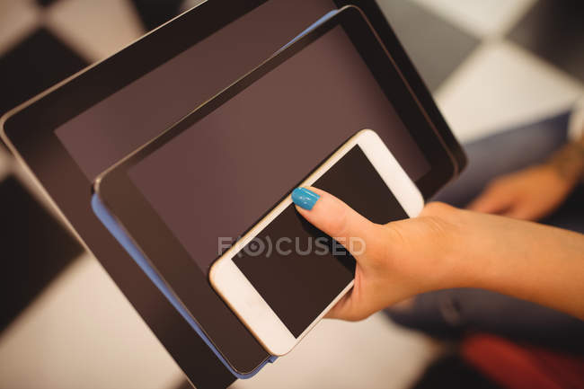 Рука жінки, що тримає мобільні та цифрові планшети в салоні волосся — стокове фото