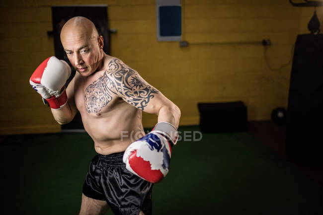 Boxeador tailandés tatuado sin camisa practicando en el gimnasio - foto de stock