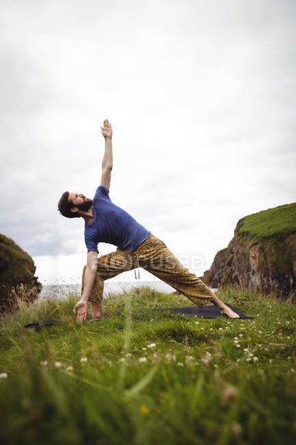Man performing stretching exercise on cliff — Stock Photo