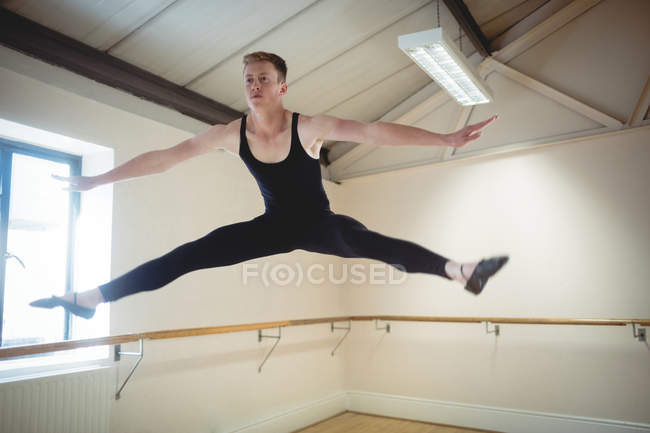 Ballerino jumping while practicing ballet dance in studio — Stock Photo