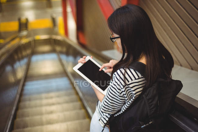 Visão traseira da mulher usando tablet digital na escada rolante — Fotografia de Stock