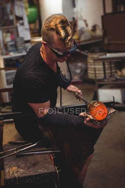 Glassblower shaping molten glass piece with wet cloth at glassblowing factory — Stock Photo