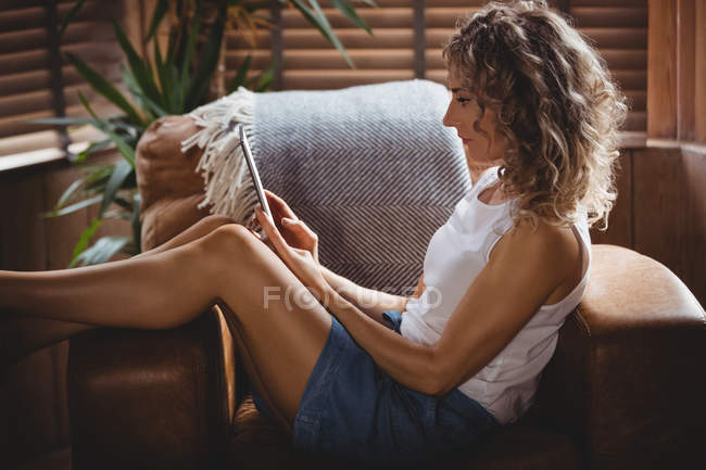 Mulher bonita usando tablet digital na sala de estar em casa — Fotografia de Stock