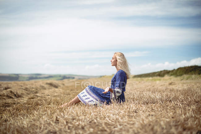 Вид збоку Безтурботна блондинка сидить у полі — стокове фото