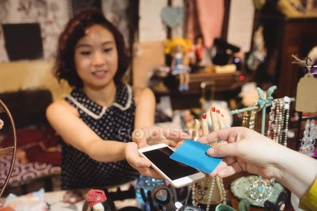 Cliente dando seu telefone e cartão de crédito para caixa no balcão de faturamento — Fotografia de Stock