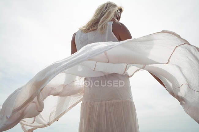 Низький кут зору жінки, що стоїть у білій сукні під час вітряної погоди — стокове фото