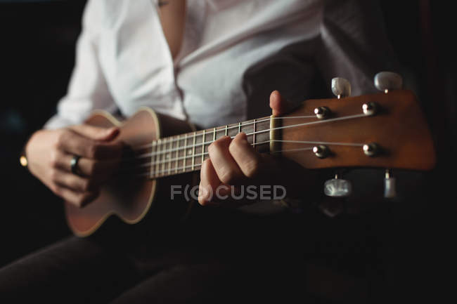 A meio da seção da mulher tocando guitarra na escola de música — Fotografia de Stock