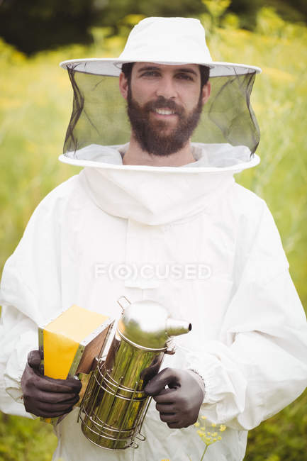 Ritratto dell'apicoltore che tiene il fumatore d'api in campo — Foto stock
