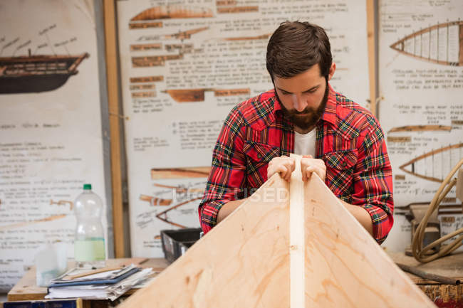 Человек готовит деревянный каркас лодки на верфи — стоковое фото