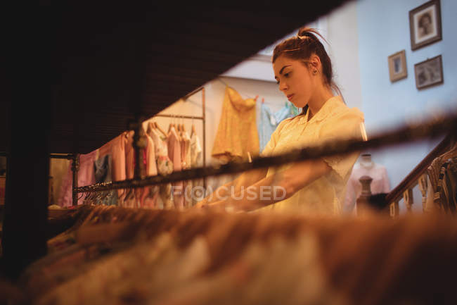 Mulher selecionando roupas em cabides na loja de roupas — Fotografia de Stock