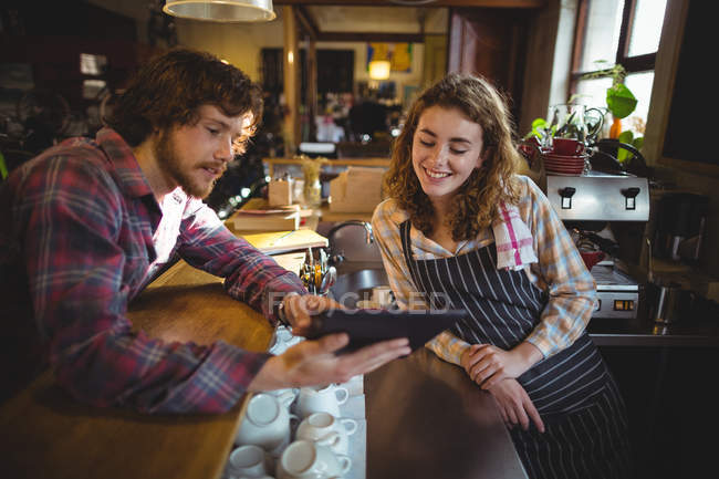Customer showing digital tablet to waitress in bicycle shop — Stock Photo