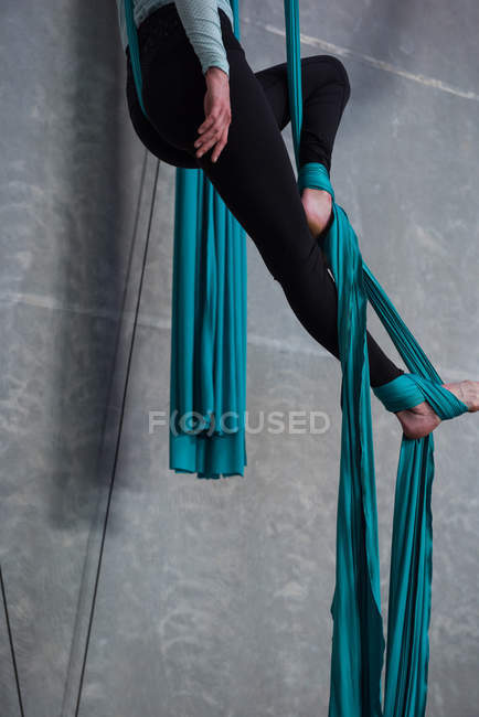 Female gymnast exercising on blue fabric rope in fitness studio — Stock Photo