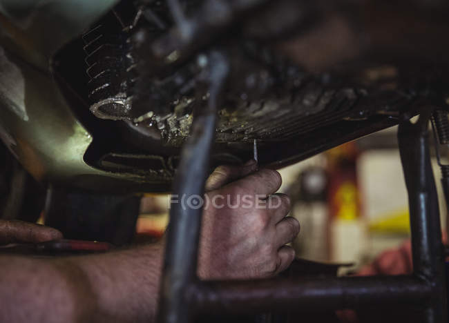 Primer plano del mecánico examinando moto en el taller - foto de stock