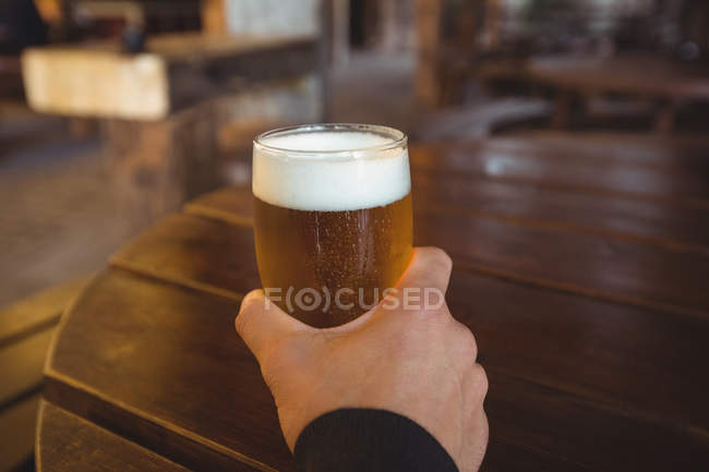 Uomo che tiene un bicchiere di birra al bar — Foto stock