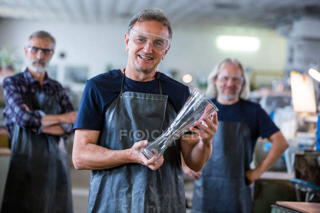 Портрет стеклодувов, держащих стеклянную вазу на стекольном заводе — стоковое фото