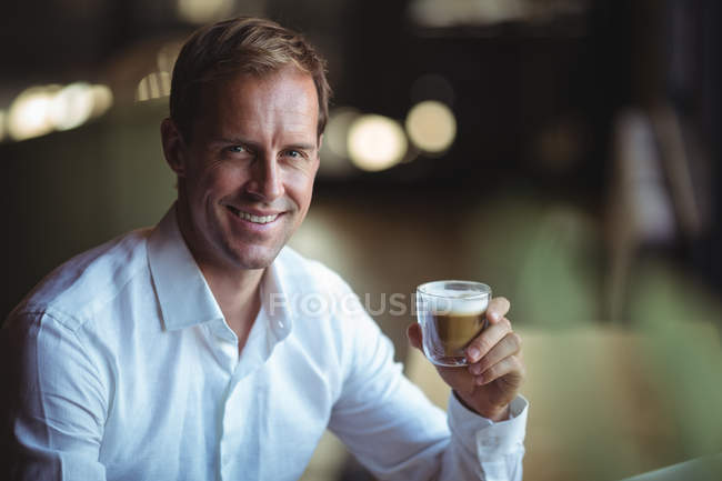 Retrato de hombre de negocios feliz sosteniendo café en la cafetería - foto de stock