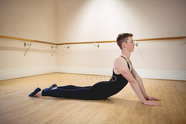 Vista lateral de bailarino alongamento no chão em estúdio — Fotografia de Stock