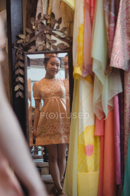 Donna che si guarda allo specchio con un vestito nuovo in boutique — Foto stock