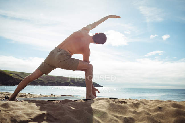 Visão traseira do homem realizando exercício de alongamento na praia — Fotografia de Stock