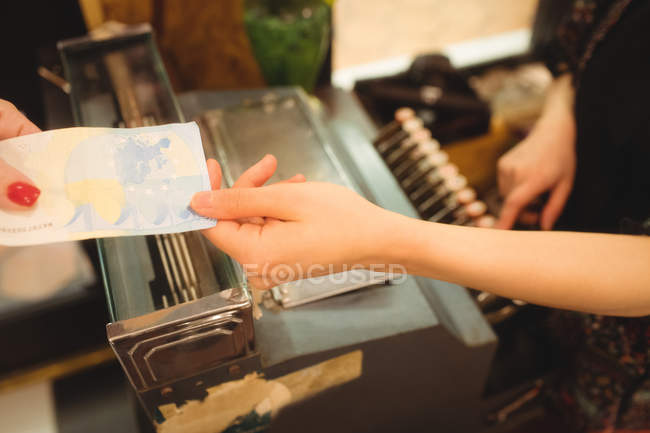 Caissière acceptant un paiement au comptoir en magasin — Photo de stock