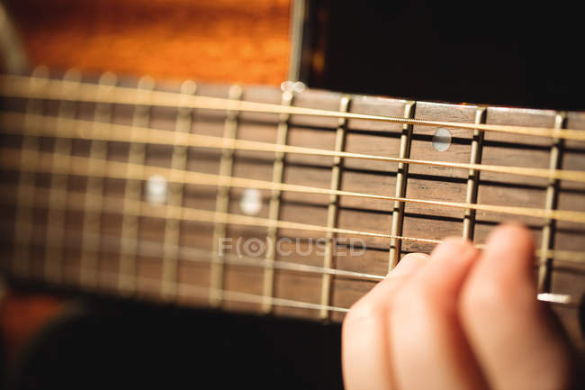 Primer plano de la mujer tocando una guitarra en la escuela de música - foto de stock