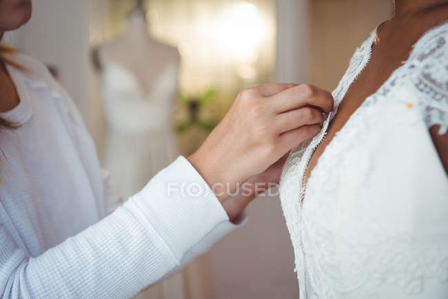 Woman trying on wedding dress in a studio with the assistance of fashion designer — Stock Photo