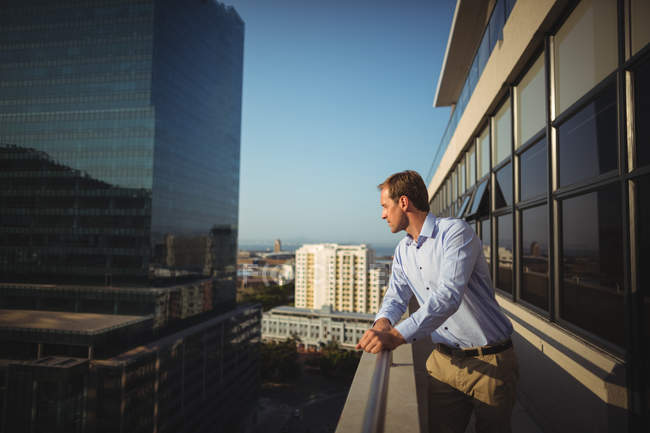 Бизнесмен, стоящий на балконе в офисе — стоковое фото