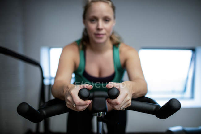 Беременная женщина тренируется на велотренажере в спортзале — стоковое фото