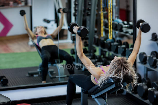 Женщина поднимает гантели в спортзале — стоковое фото