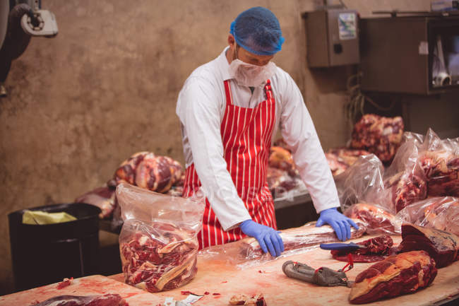 Boucher emballant la viande rouge dans la salle d'entreposage à la boucherie — Photo de stock