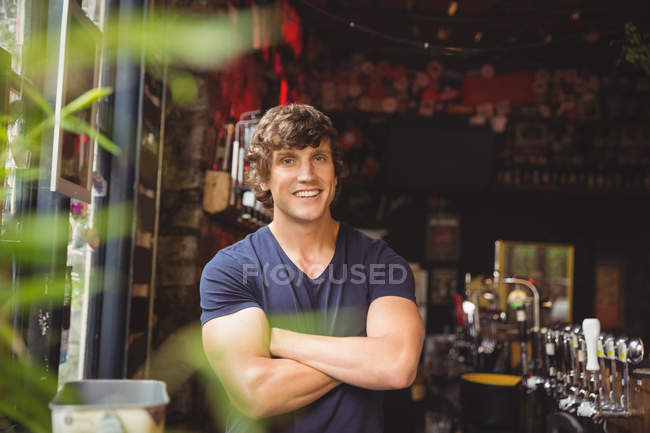 Portrait of bar tender standing with arms crossed at bar counter — Stock Photo