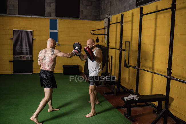 Vista lateral de dois boxers tailandeses esportivos praticando no ginásio — Fotografia de Stock