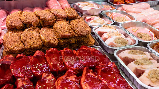 Variedad de carne marinada en mostrador en carnicería - foto de stock