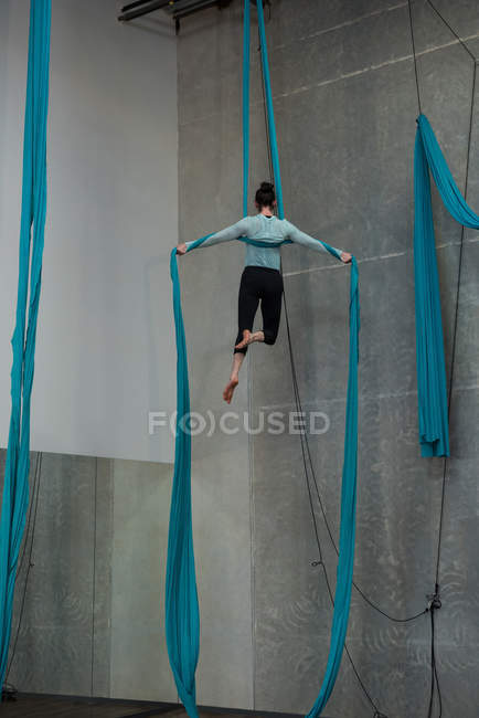 Gymnaste s'exerçant sur corde en tissu bleu dans un studio de fitness — Photo de stock