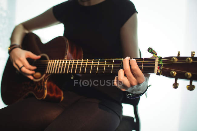 Mid-section of woman playing a guitar in music school — Stock Photo