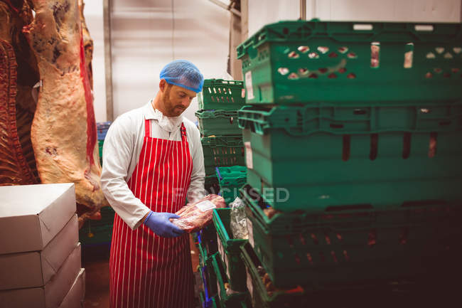 Carnicero arreglando la carne en cajas en la carnicería - foto de stock