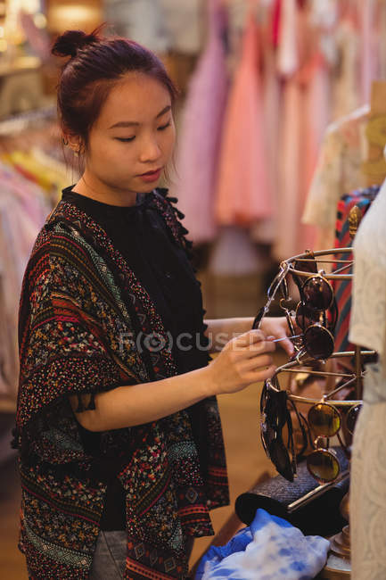 Femme élégante sélectionnant des lunettes de soleil dans une boutique de bijoux anciens — Photo de stock