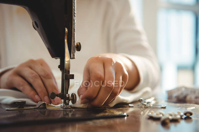 Sección media de costura de costura femenina en la máquina de coser en el estudio - foto de stock